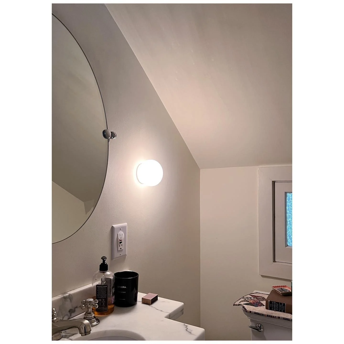 Bathroom before wallpaper with pale walls, a round mirror and white pedestal basin