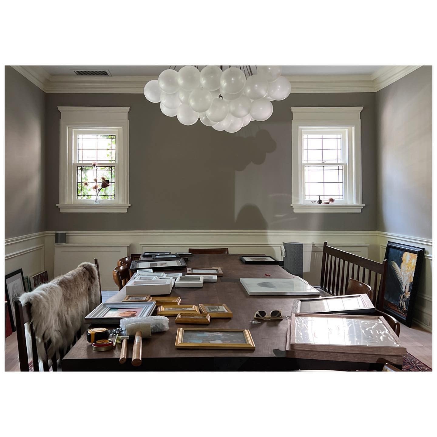 Dining room before the gallery wall installation with framed works laid across the table