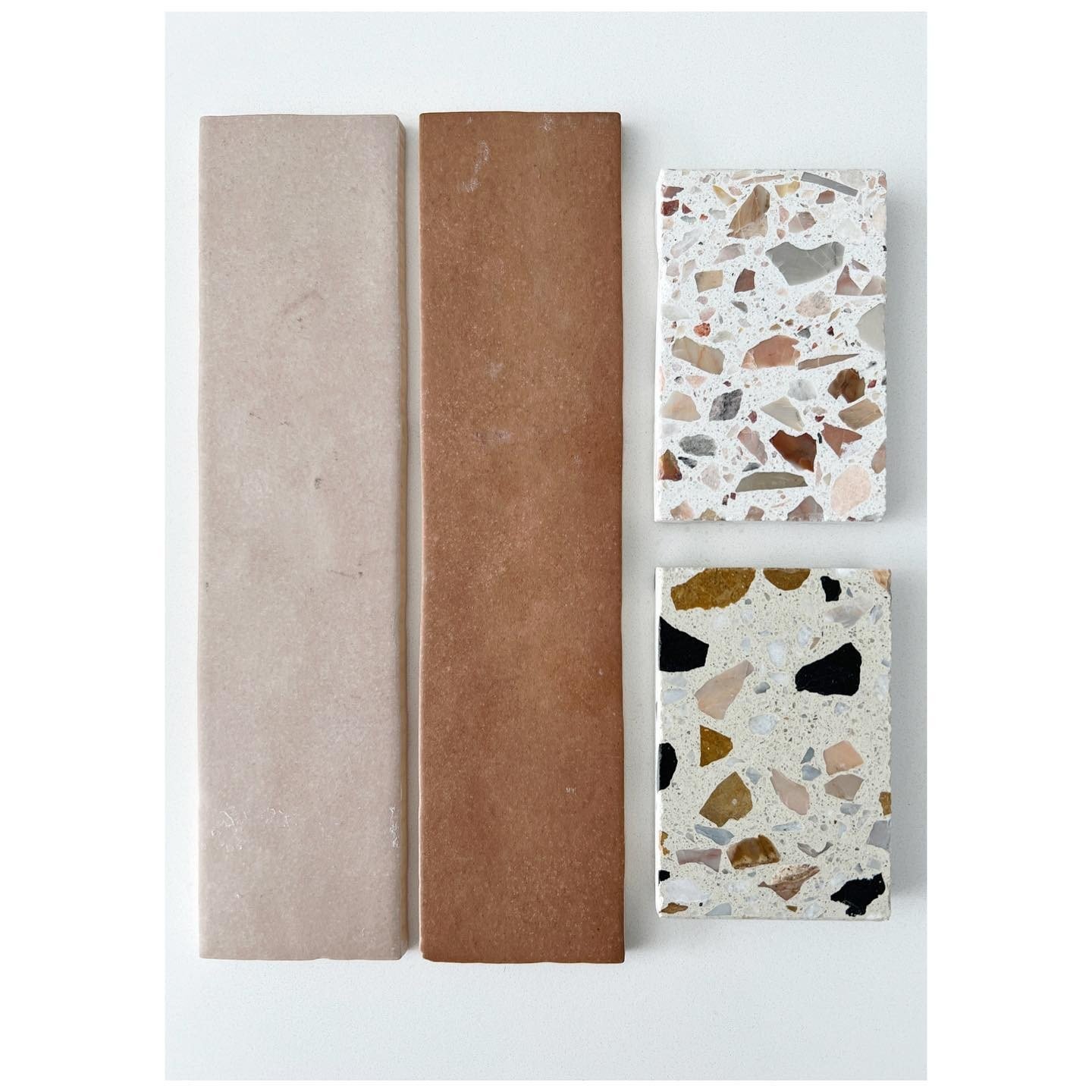 Two long muted clay tile samples beside pale terrazzo samples with warm and cool stone chips
