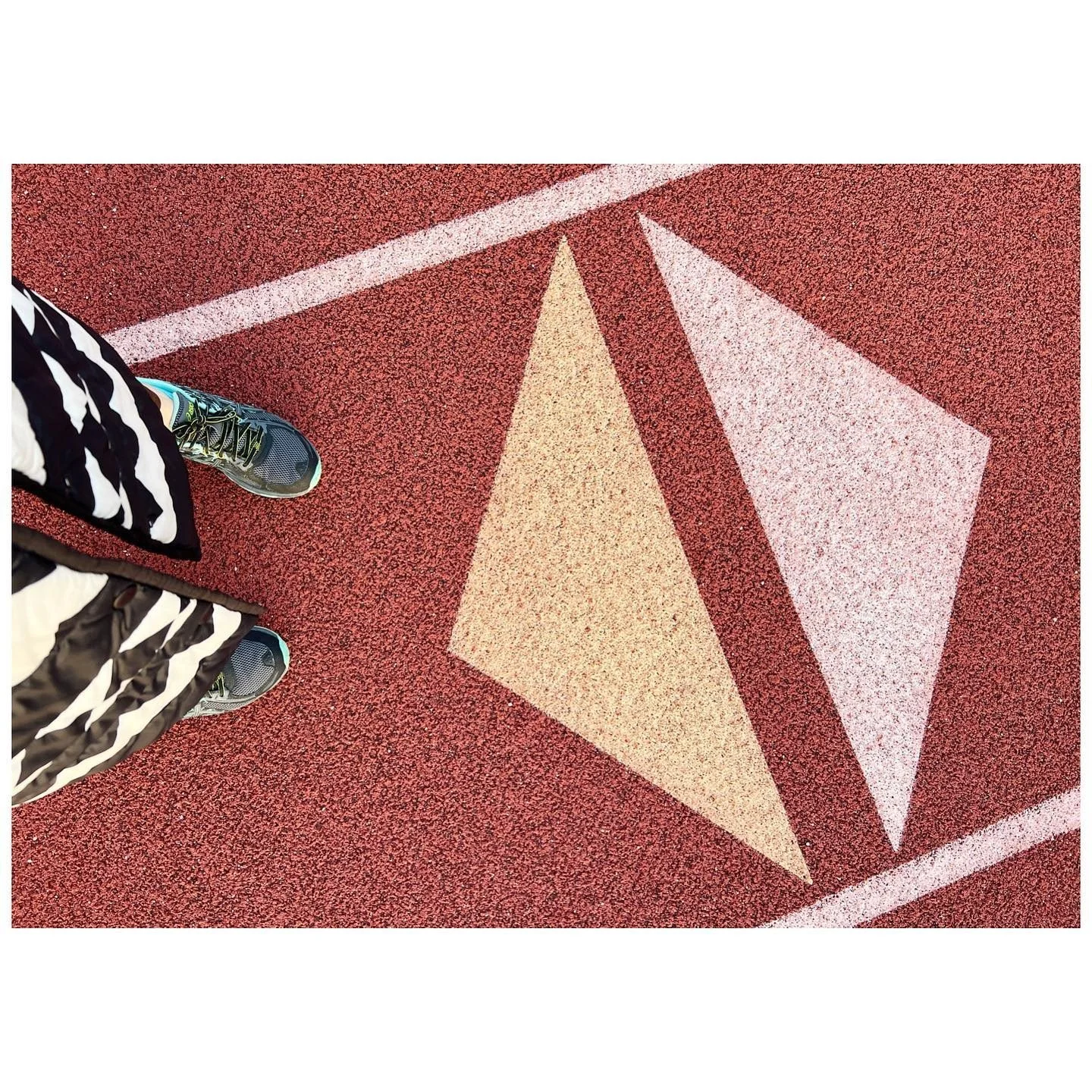 Pale pink and yellow geometric track markings on a red textured surface