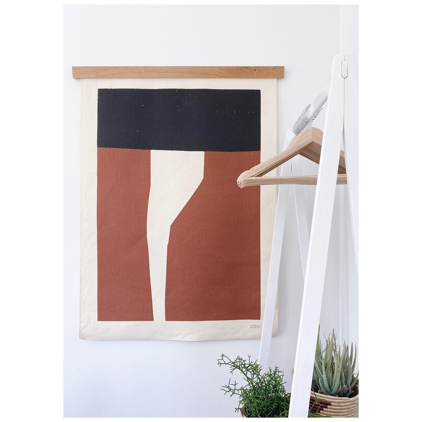Graphic rust, black and cream canvas hanging beside a white stair railing