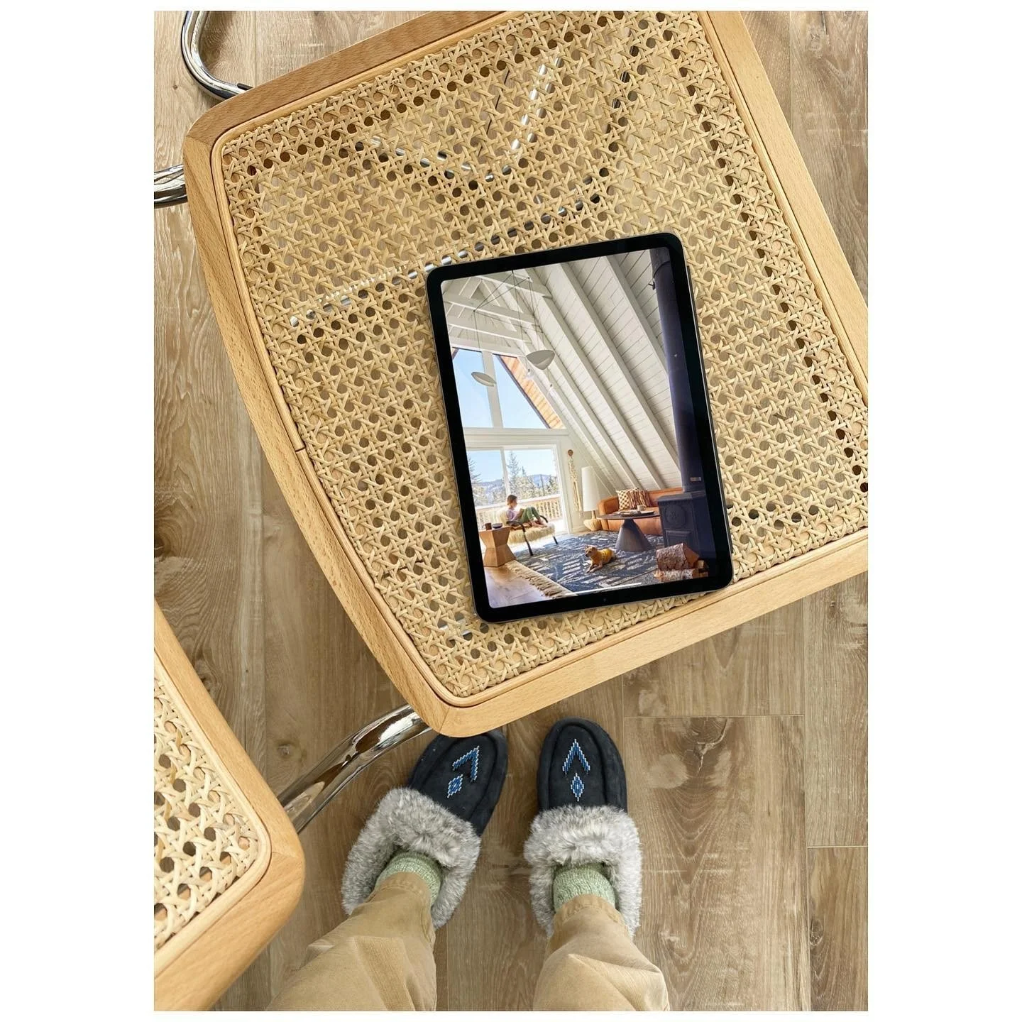 Tablet showing an interior photograph resting on a cane chair during a cabin photoshoot