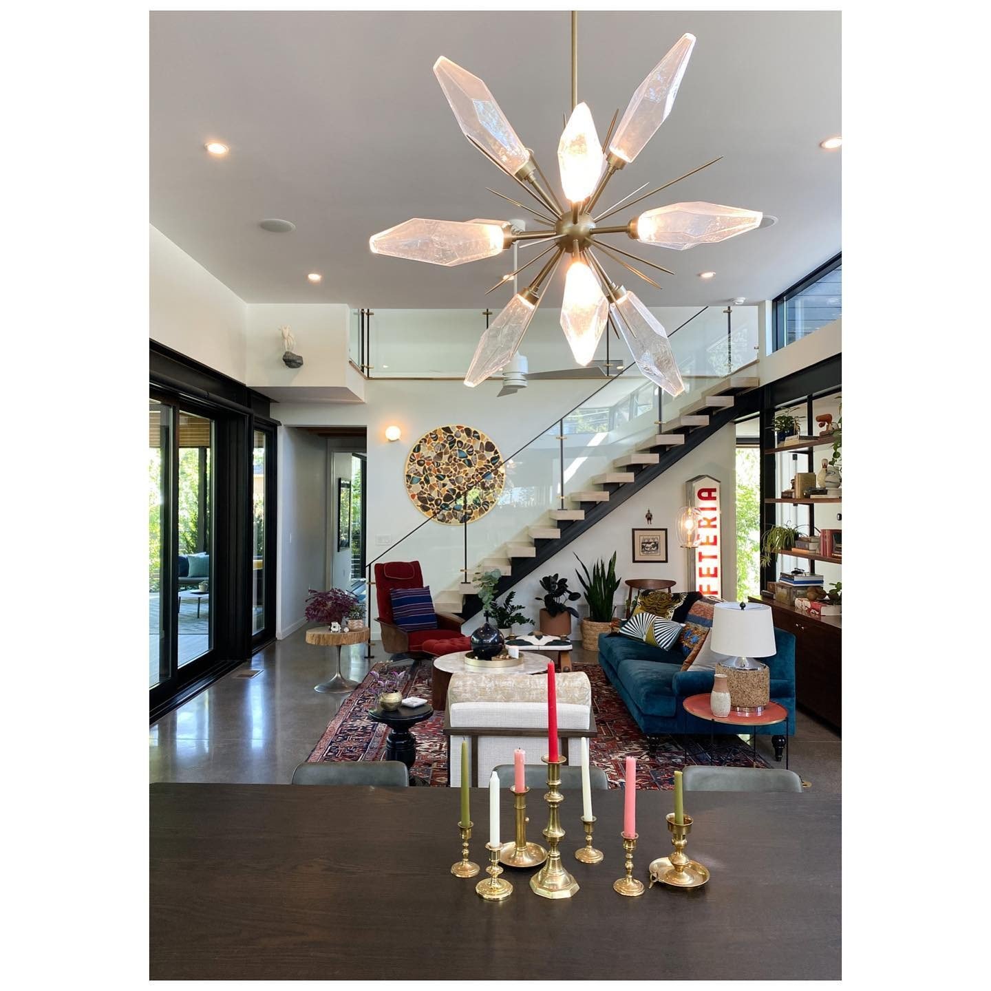 Open living and dining room with sculptural glass lighting, colorful furnishings and an open staircase