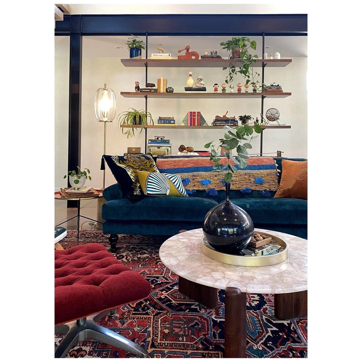 Deep blue sofa with patterned cushions, red tufted seating and a large round coffee table