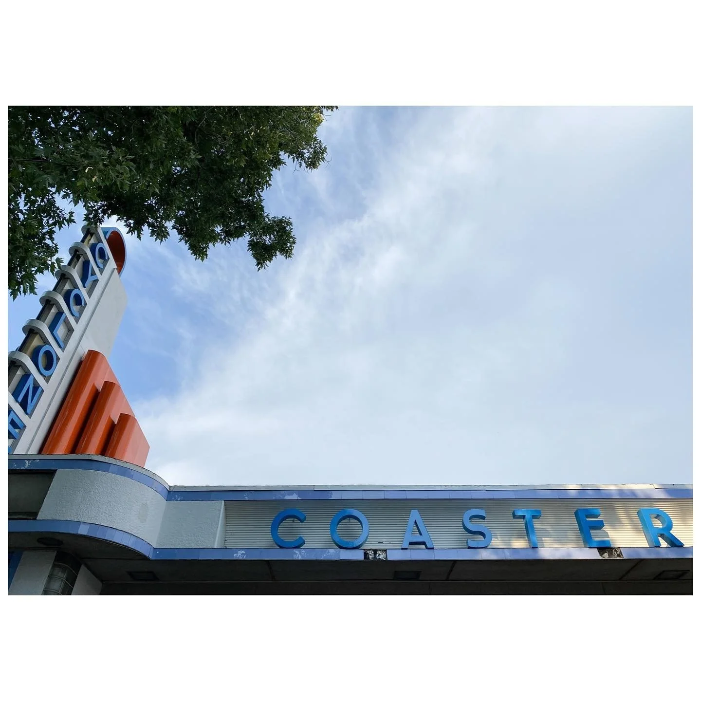 Art Deco-style blue and orange Coaster lettering beneath a pale sky