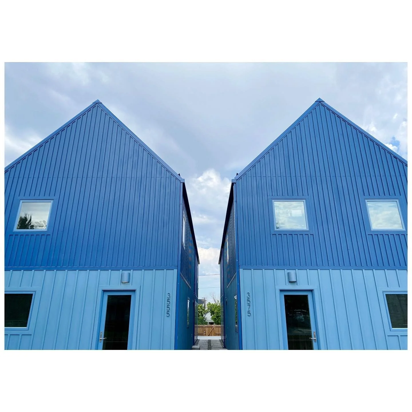 Two narrow gabled buildings clad in vivid blue standing-seam metal