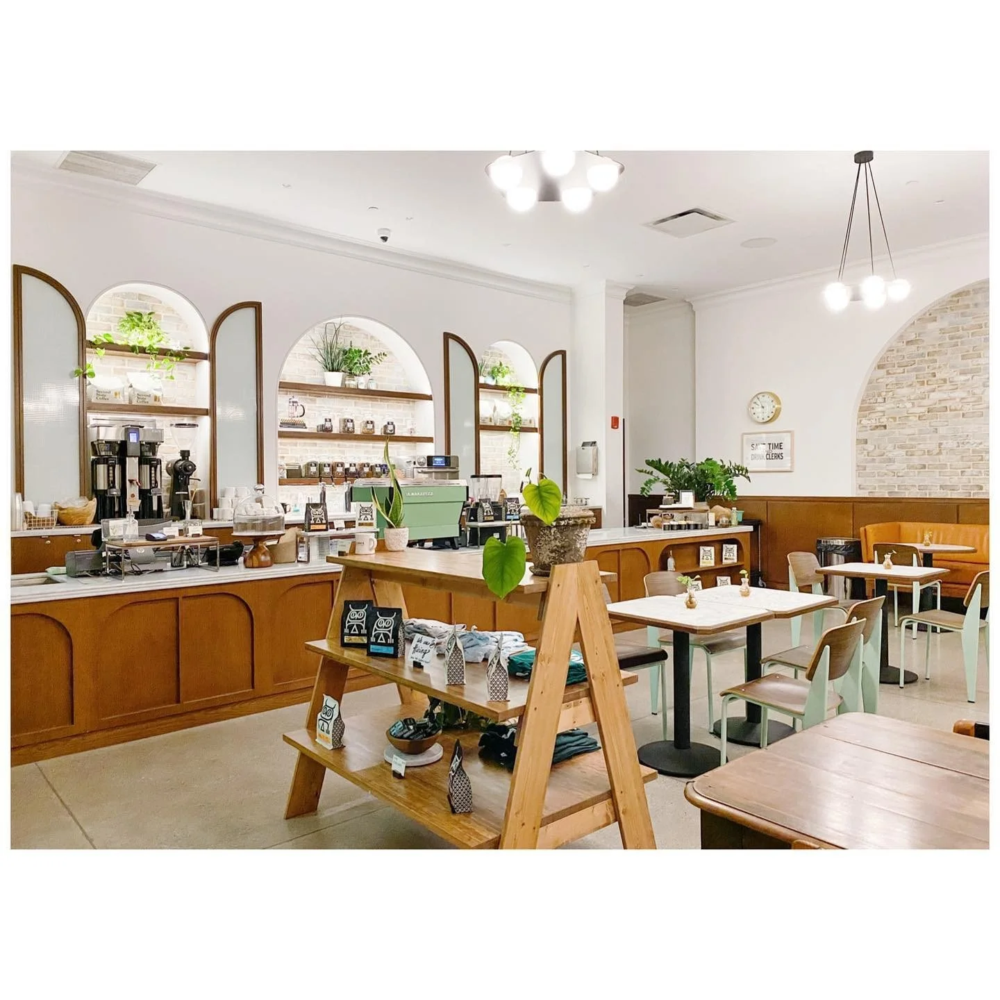 Coffee counter with warm timber cabinetry, arched shelves, pale green chairs and white walls