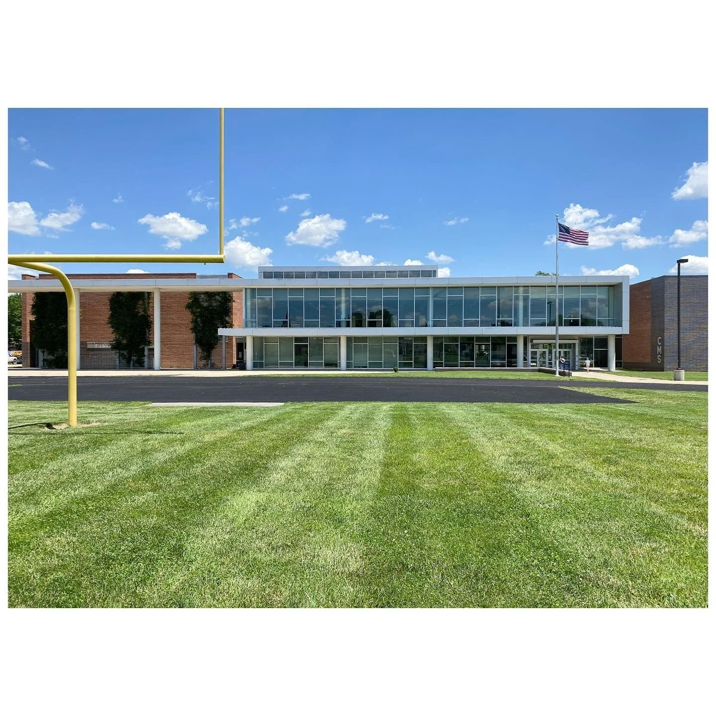 Low modernist building with a long glazed facade and bright green lawn