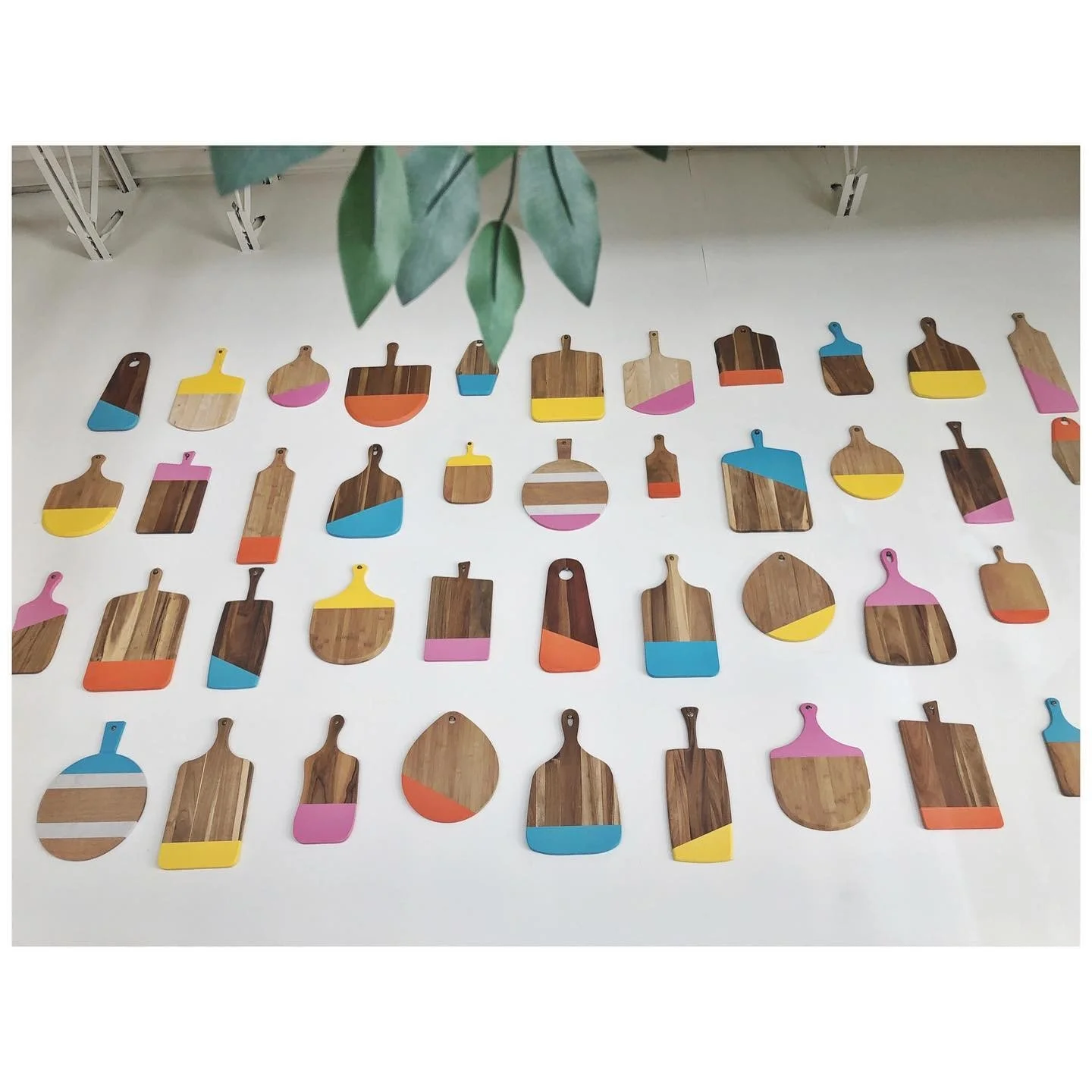 Completed installation of colorful cutting boards across a tall white restaurant wall