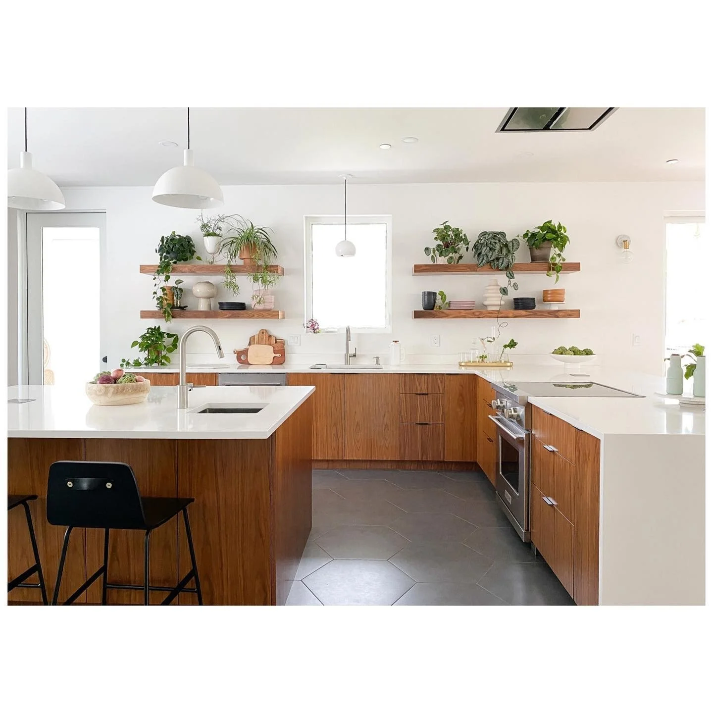 Bright kitchen with warm timber cabinets, white countertops, open shelves, plants and a gray hexagonal tile floor