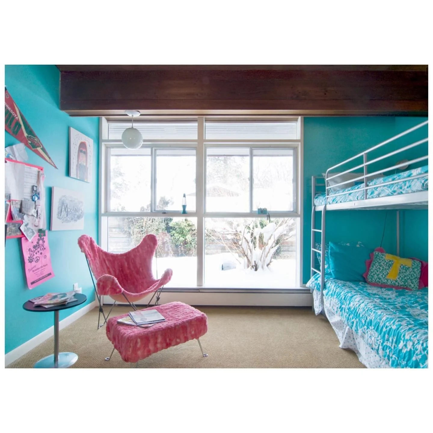 Earlier room with turquoise walls, a metal bunk bed and a bright pink lounge chair