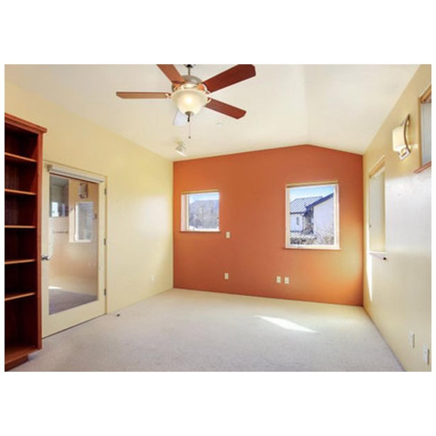 Bedroom before renovation with carpet, pale yellow walls and an orange accent wall