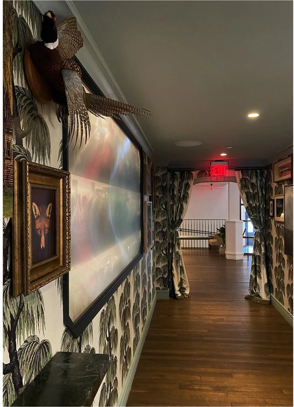 Gallery wall and botanical wallpaper along a hotel passage