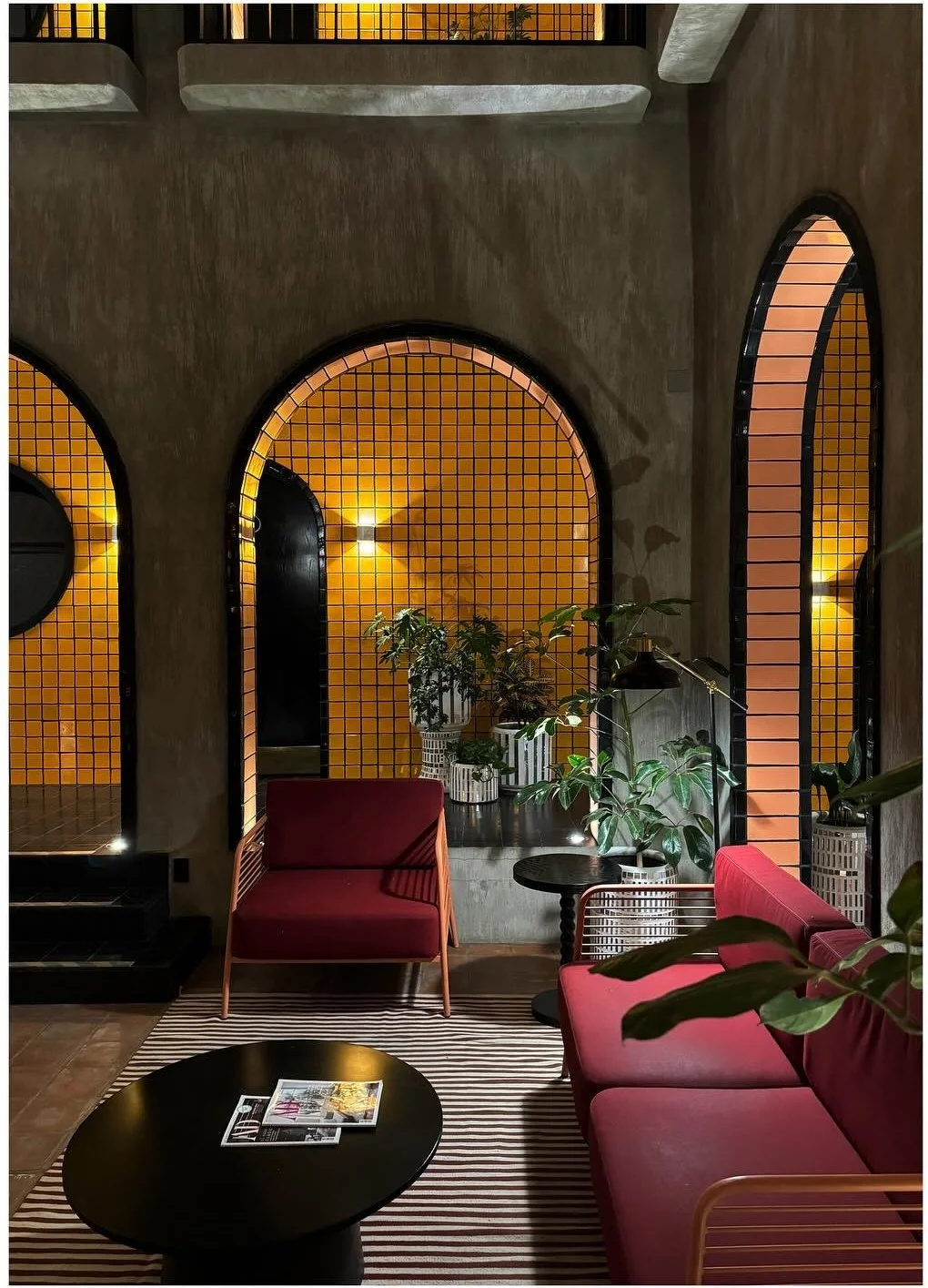 Dark lounge with yellow tiled arches and pink upholstered chairs