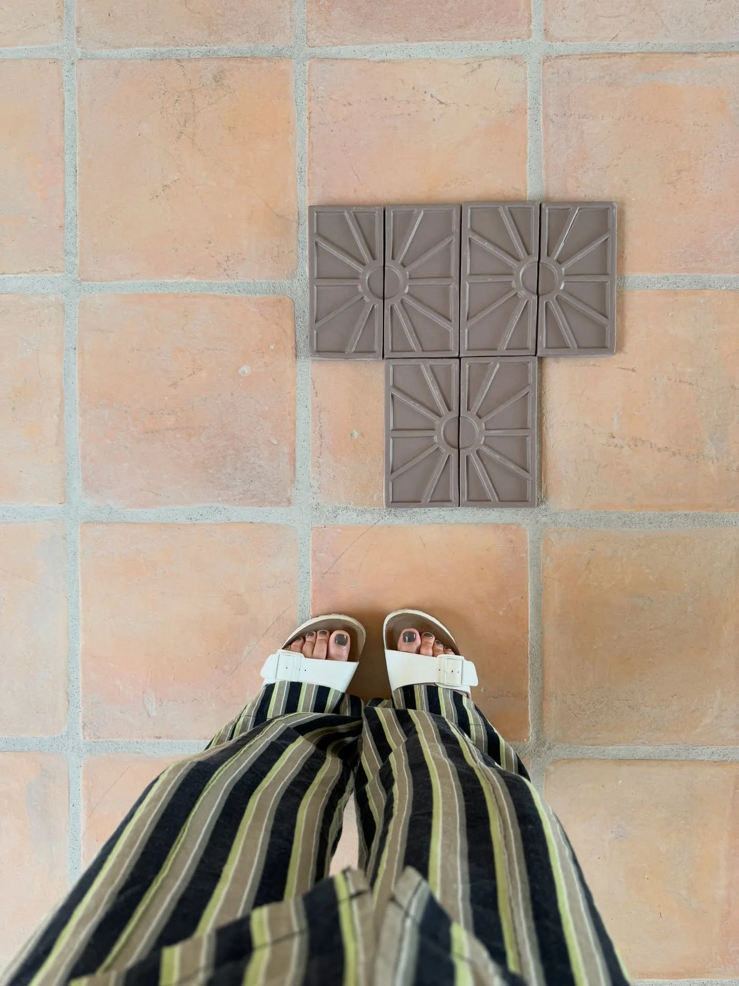 Charcoal relief tile samples laid on terracotta flooring