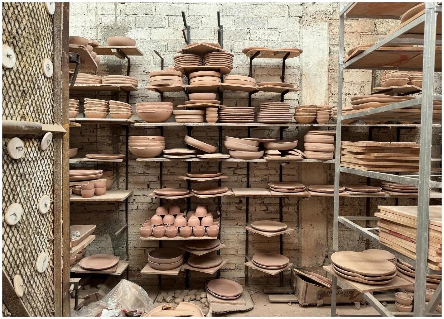 Racks of unfinished clay plates and vessels in a workshop