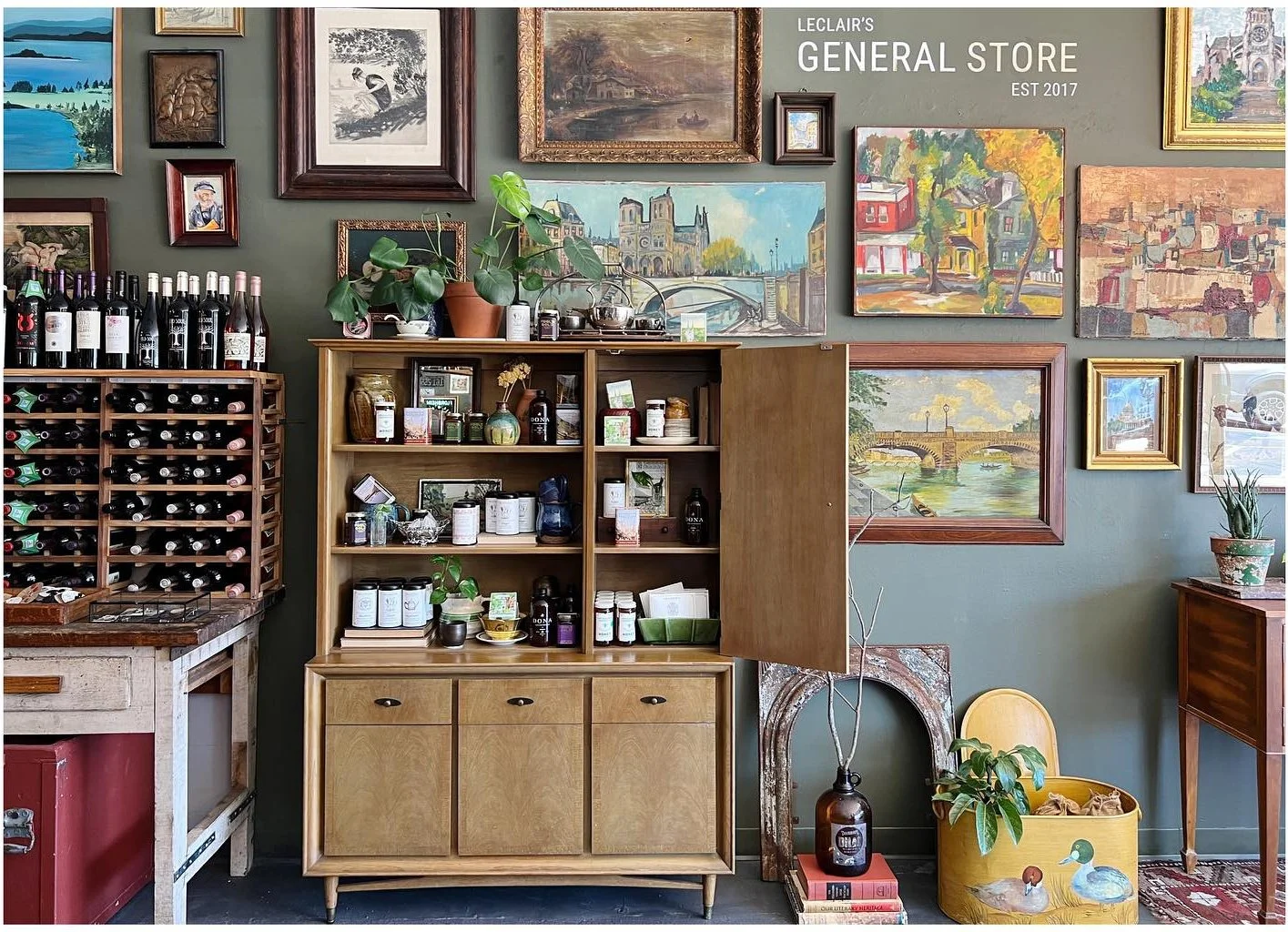 Paintings signs and small objects arranged above a wood shop cabinet
