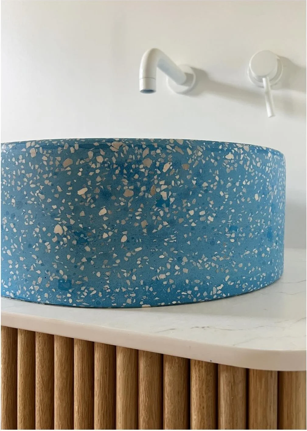Close-up of blue terrazzo basin with white stone counter