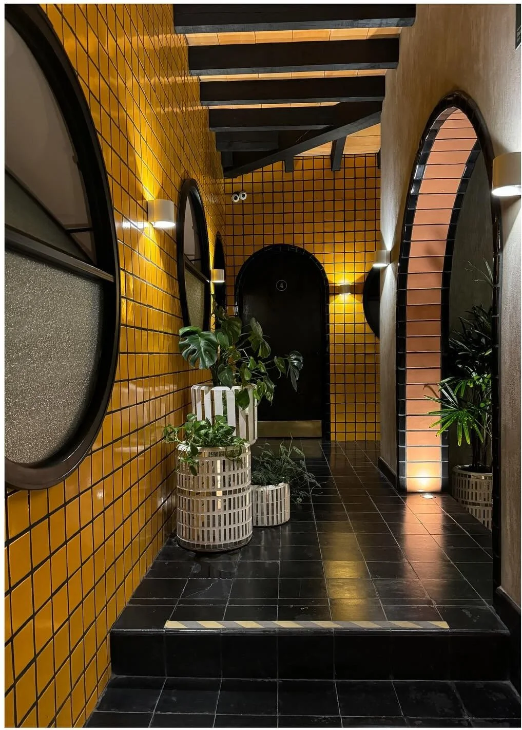 Yellow tiled corridor with circular windows and dark stone flooring