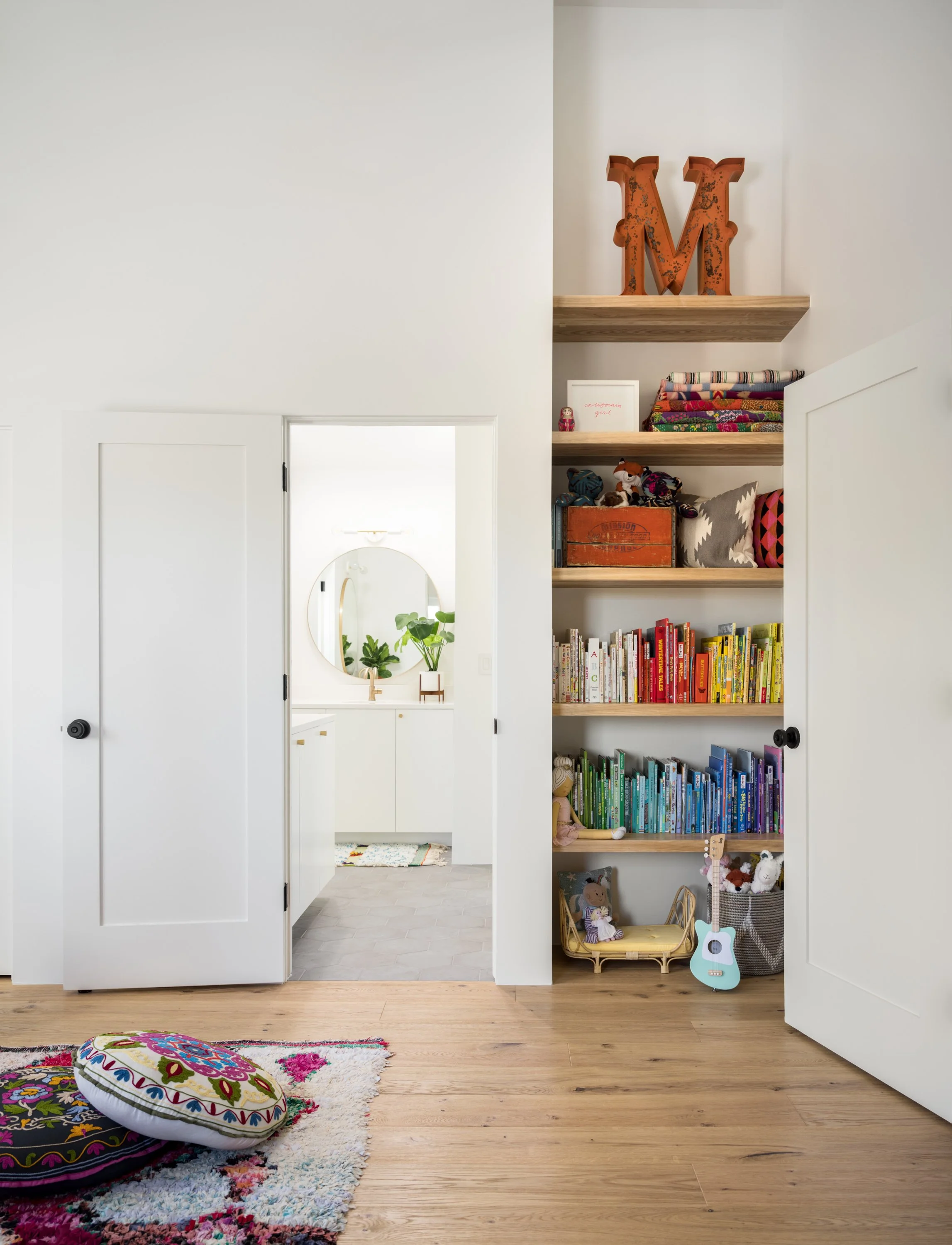 Built-in shelves of books and toys beside a bathroom doorway.