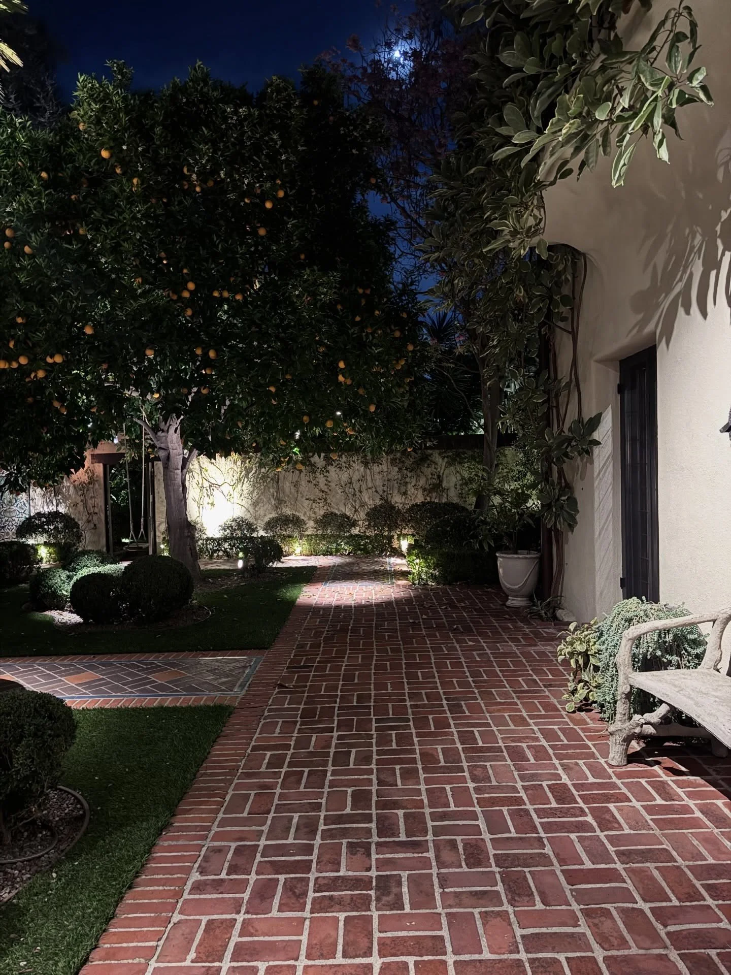 Brick courtyard path with clipped shrubs and stucco arches