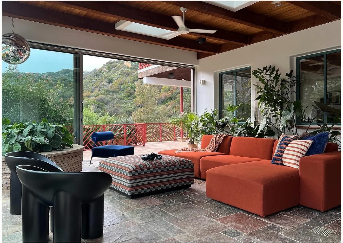 Orange outdoor sofa and patterned seating beneath exposed wood beams