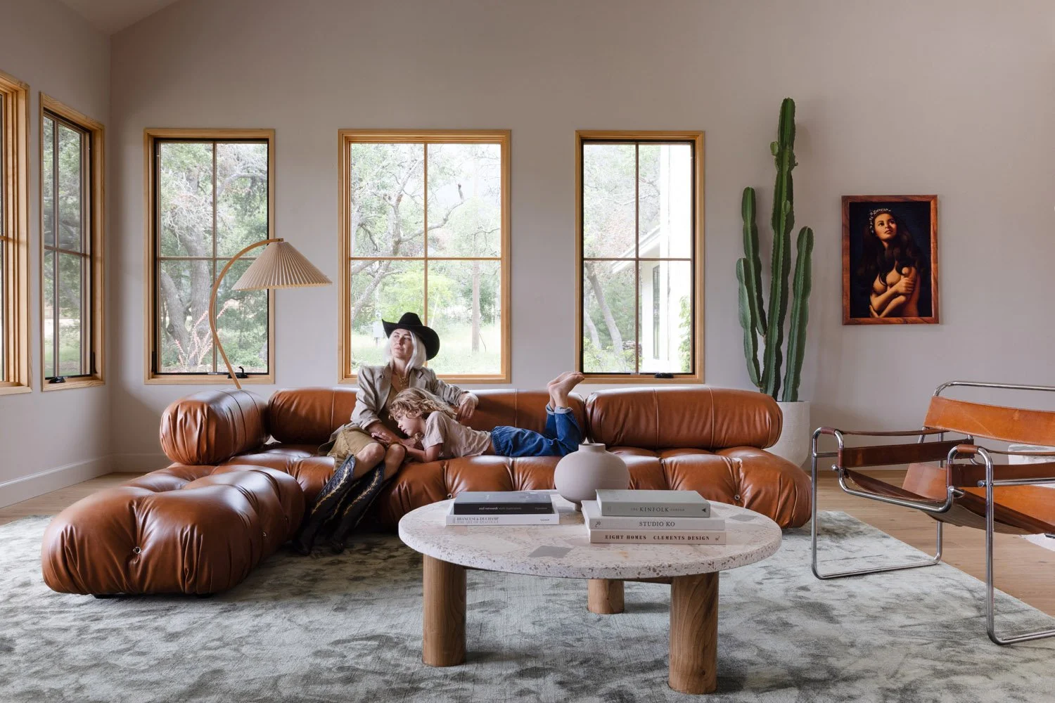 Living room with a rust-colored sofa, round coffee table, and tall windows.