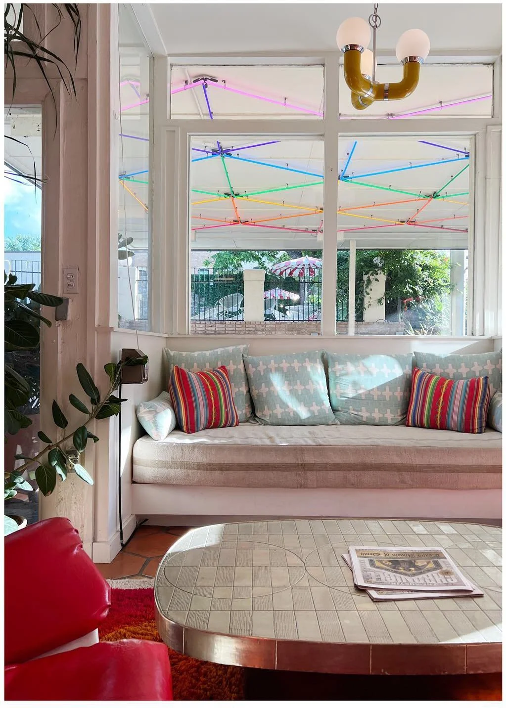 Colorful motel sitting area with a curved pale sofa red chair and large window