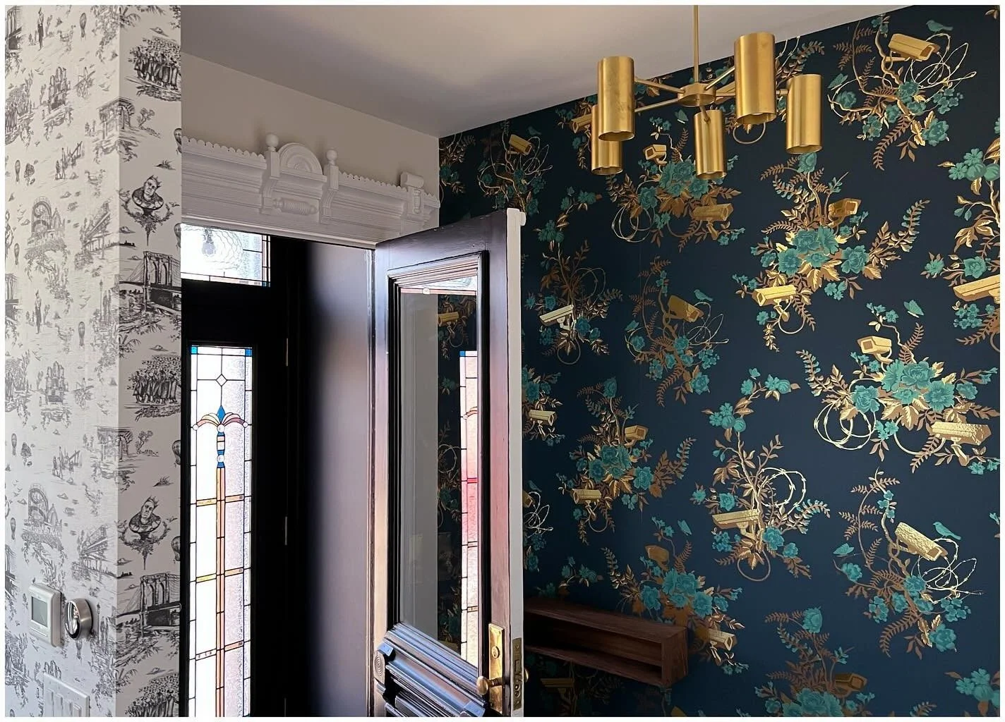 Dark botanical wallpaper beside a doorway with pale trim