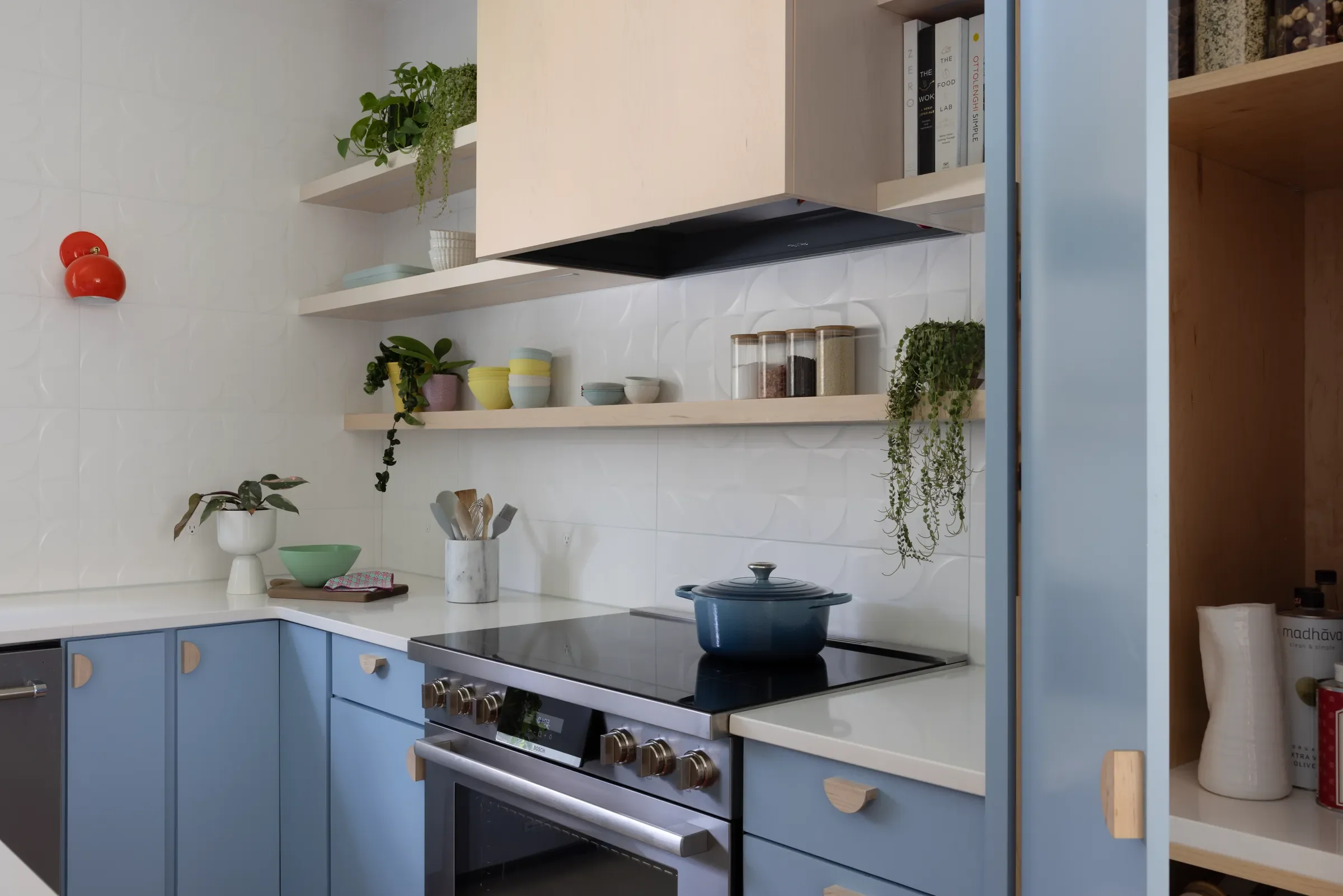 Kitchen with blue lower cabinets, open shelves, and a blue pot on the stove.