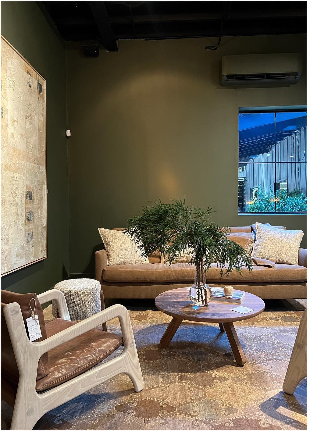 Showroom sitting area with timber chairs low tables and pale upholstery
