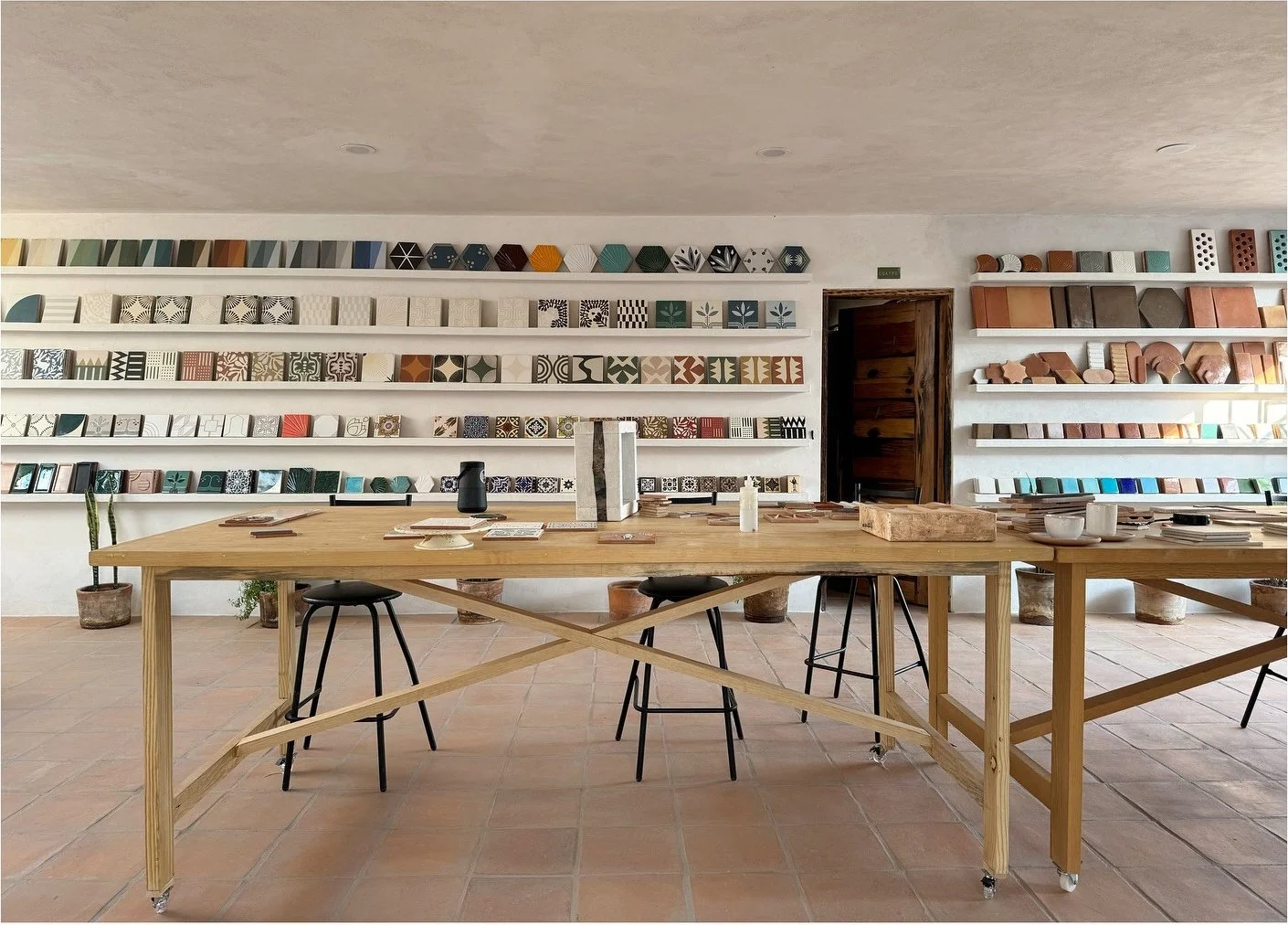 Tile workshop with long tables and rows of glazed samples