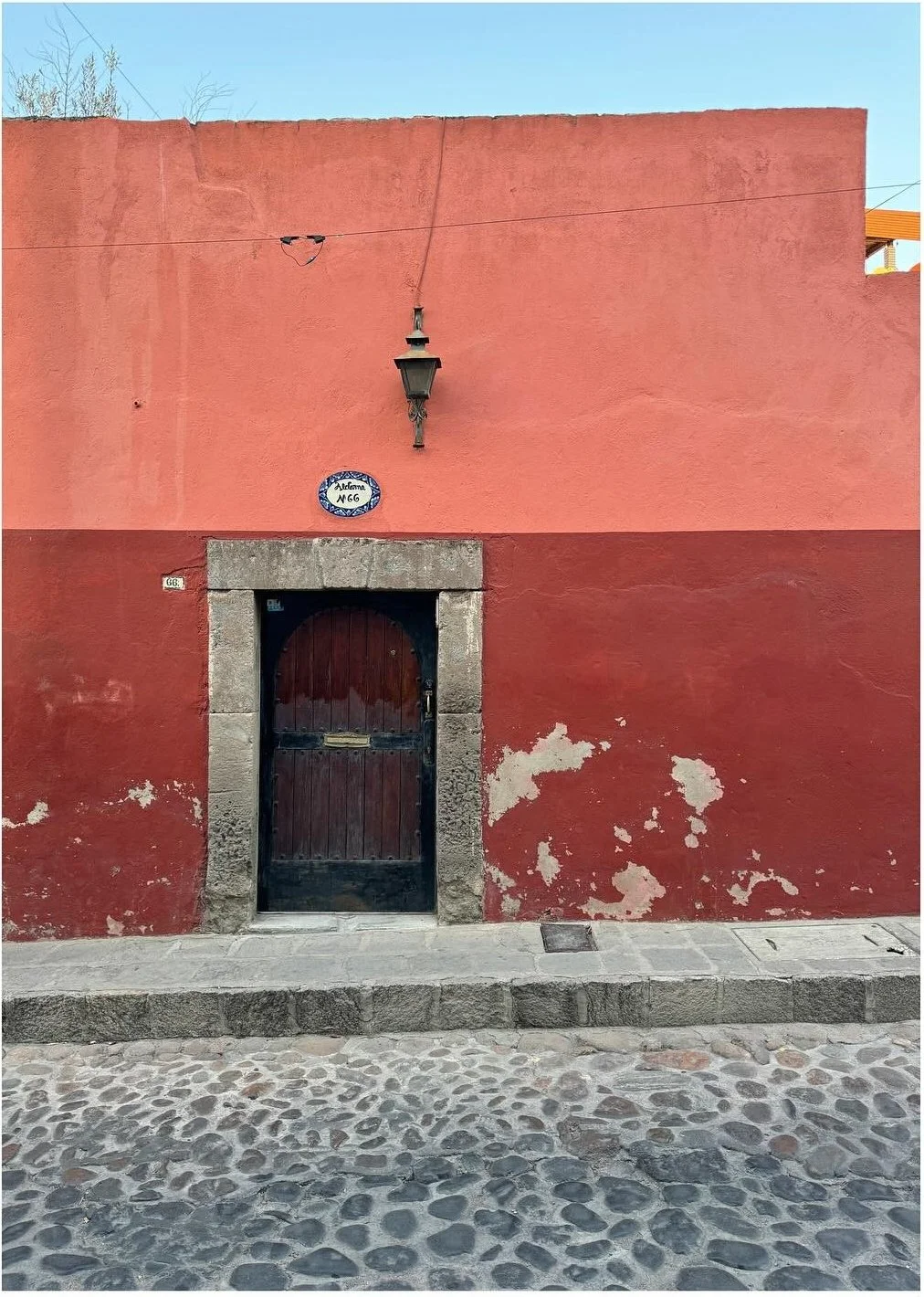 Faded coral facade with a dark doorway and cobbled pavement
