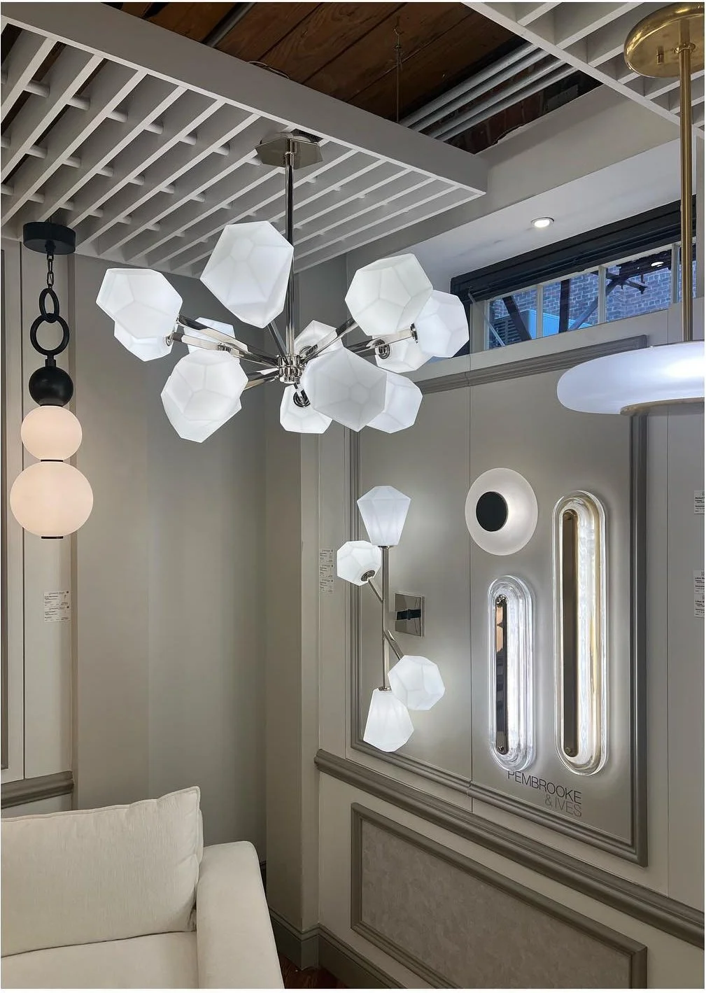 Clustered white pendants and geometric wall lights in a showroom
