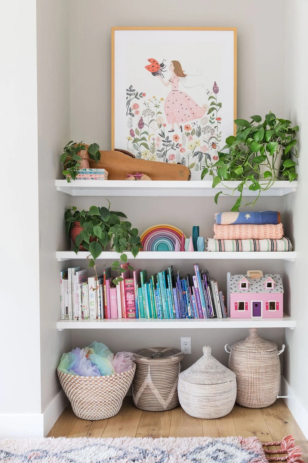 Bookshelves filled with colorful books, plants, toys, and woven baskets.