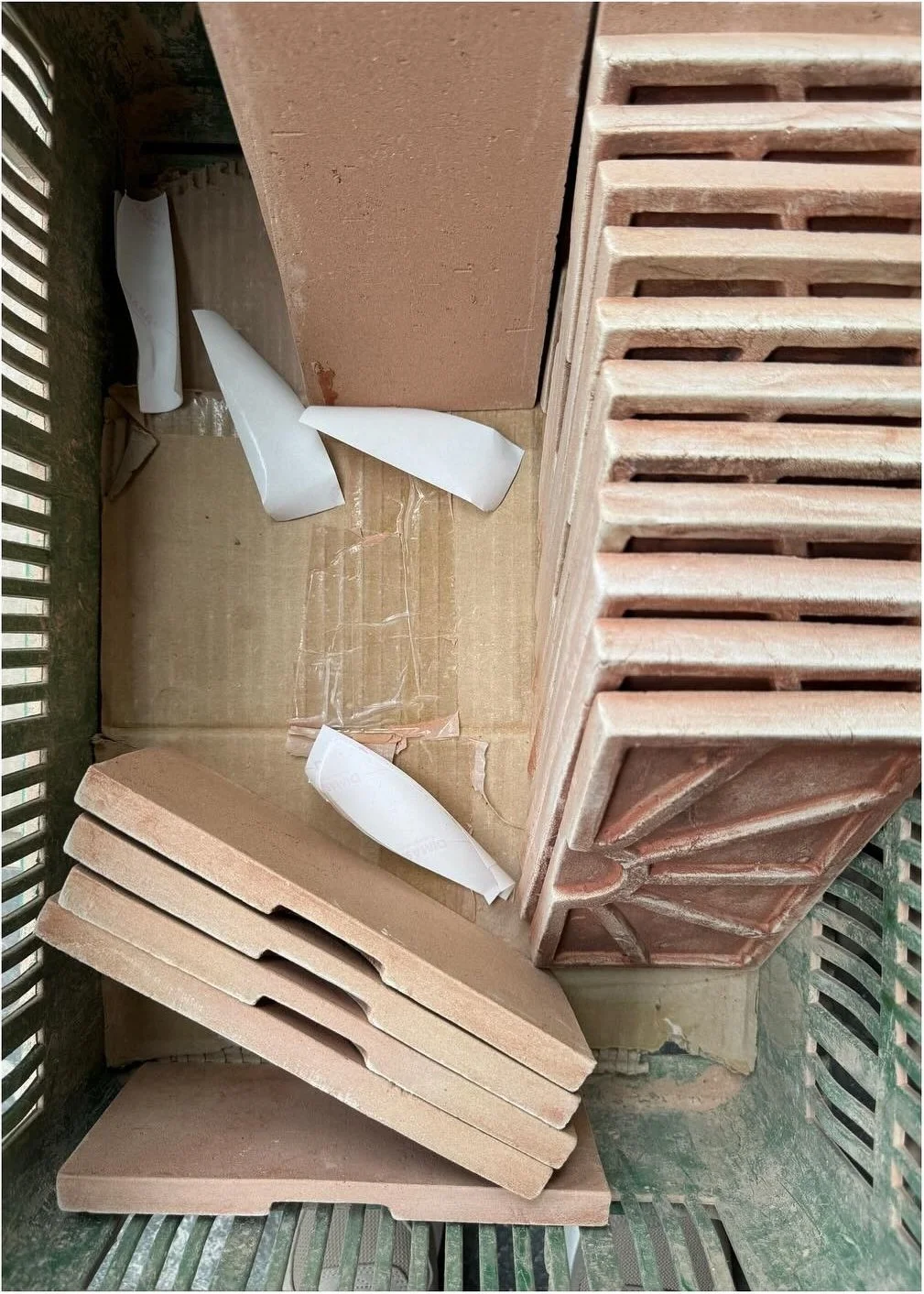 Pale clay trim pieces stacked beside ridged terracotta tiles