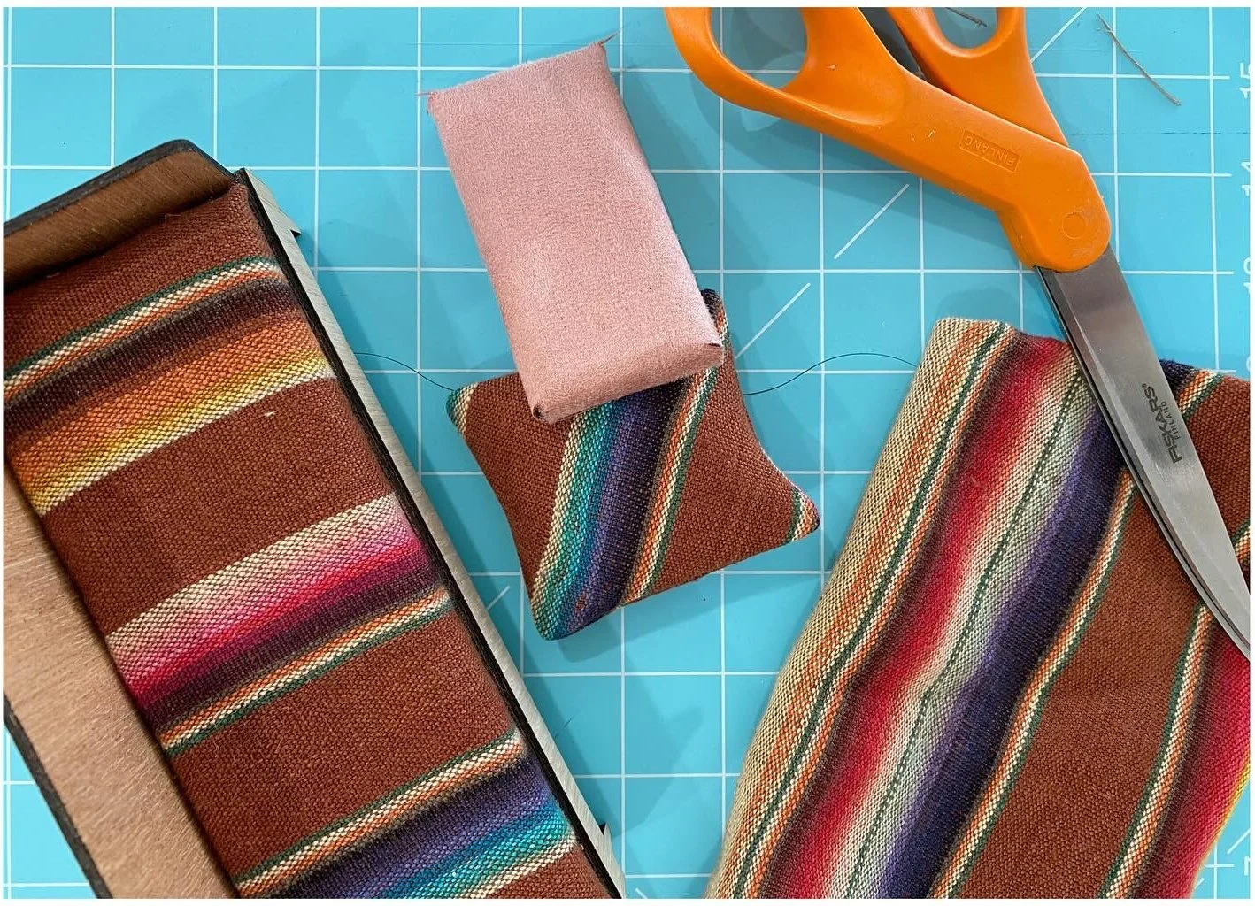 Striped fabric pieces and orange scissors on a cutting mat