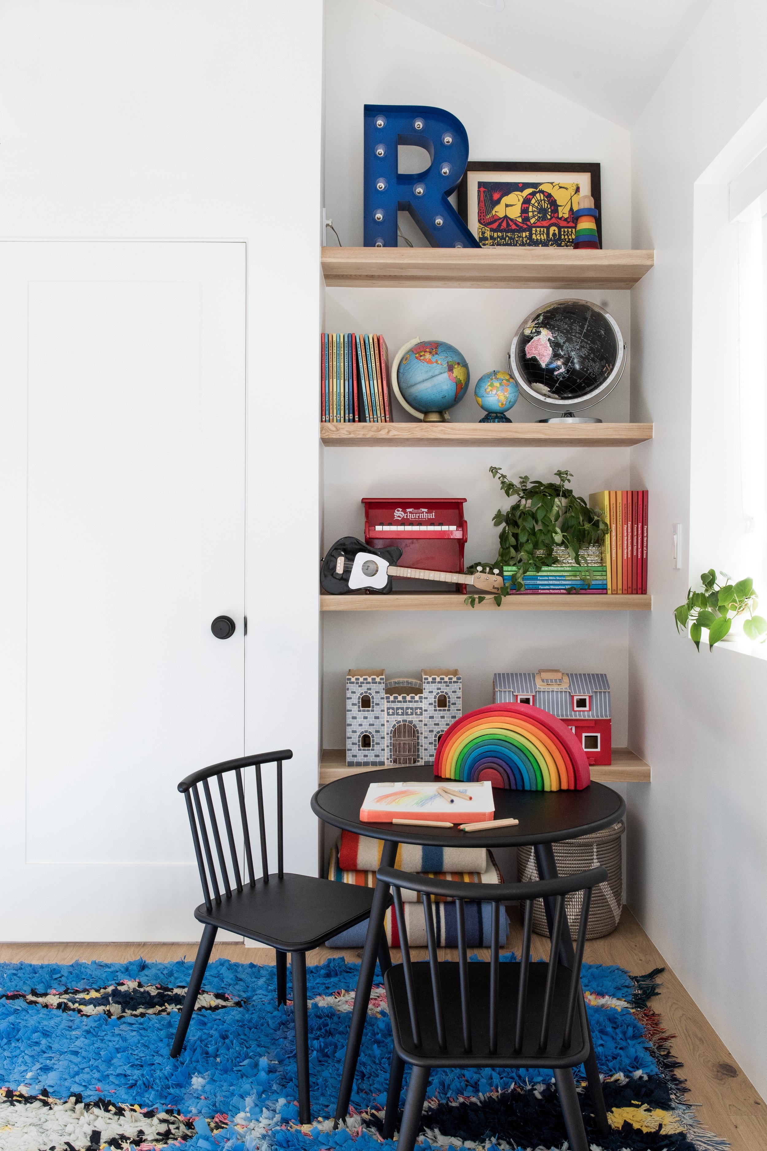 Children’s table and chairs beside shelves of books and toys.
