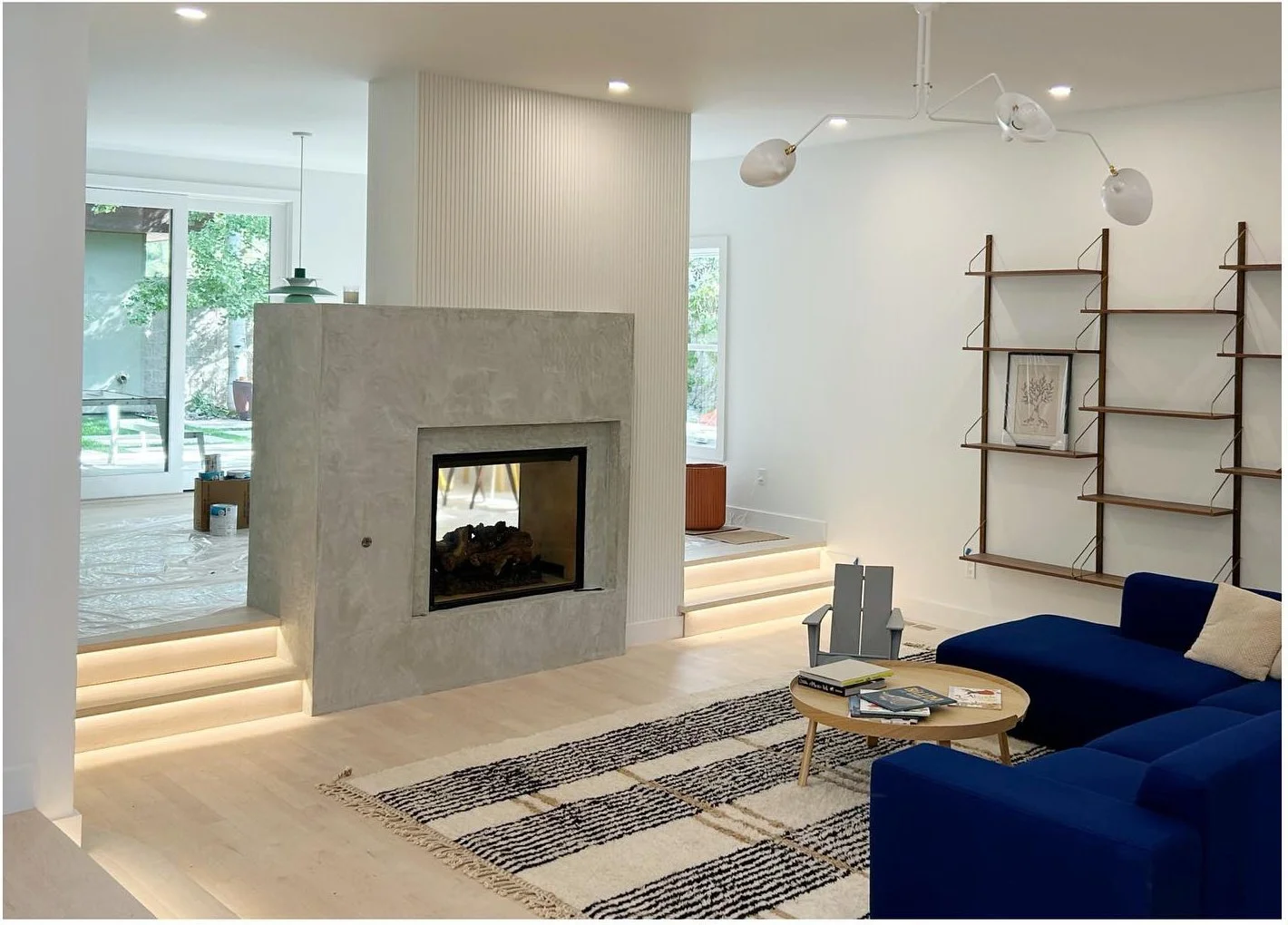 Gray fireplace wall beside open shelving and a blue sofa