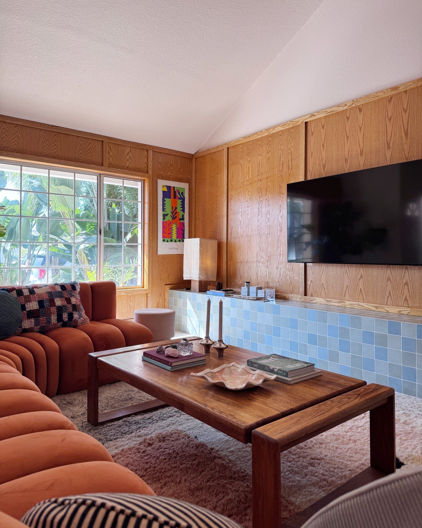 Wood-paneled living room with an orange sofa and blue tile