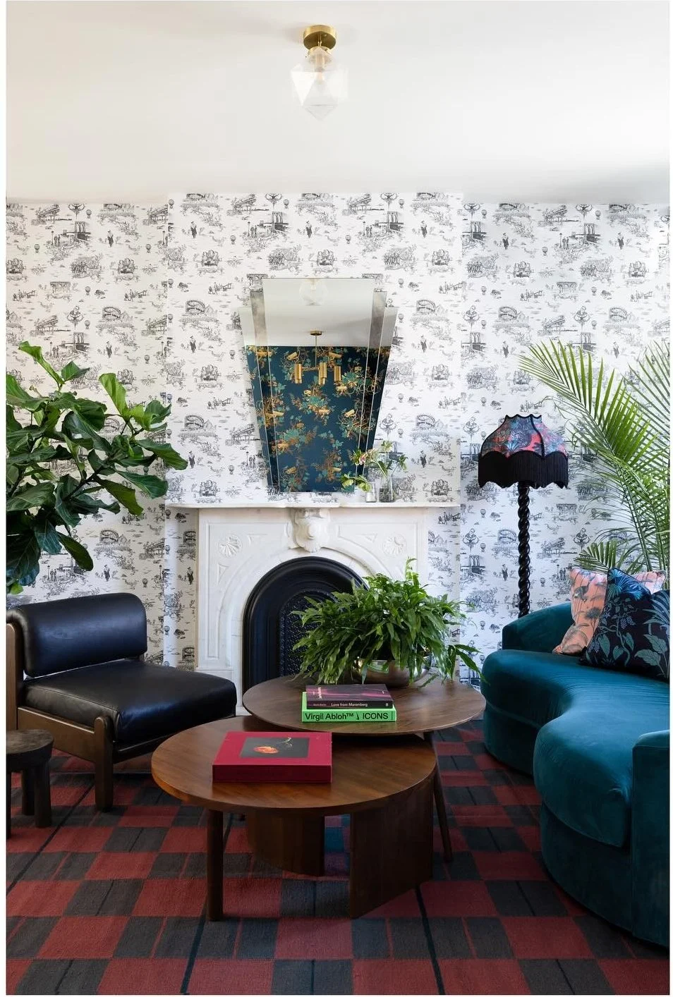 Teal sofa and vintage chair against black-and-white illustrated wallpaper