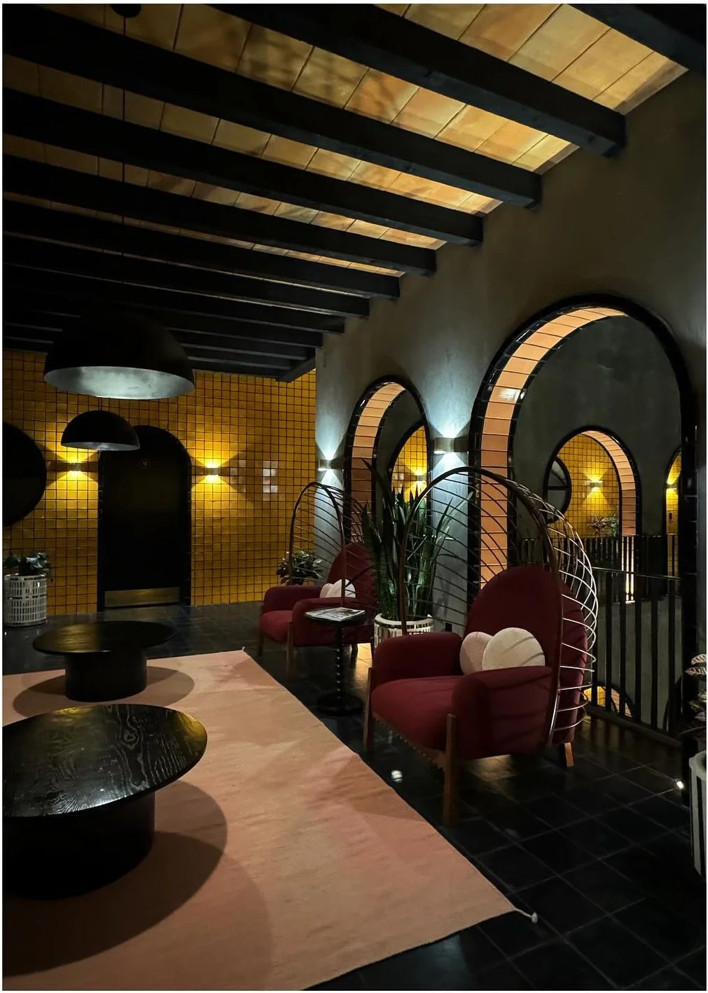 Dark lounge with pink chairs and exposed ceiling beams