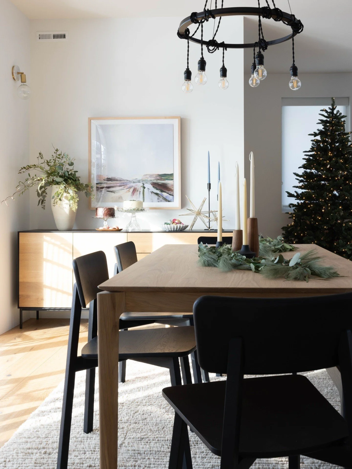 Dining table with black chairs and a circular chandelier