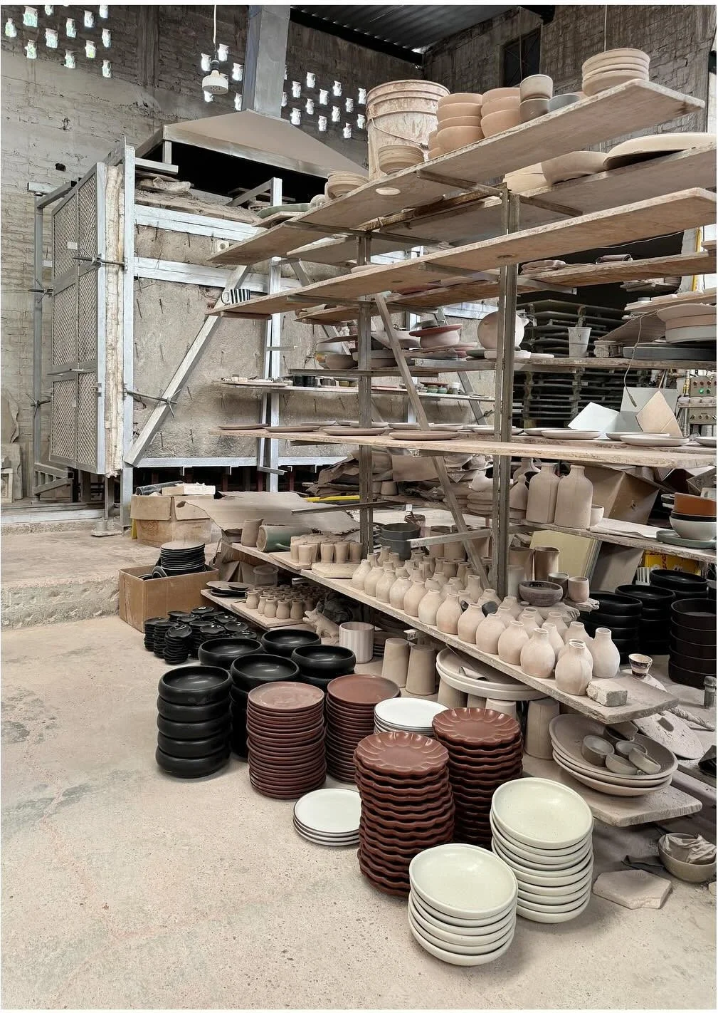 Long workshop shelves filled with ceramic bowls plates and vessels