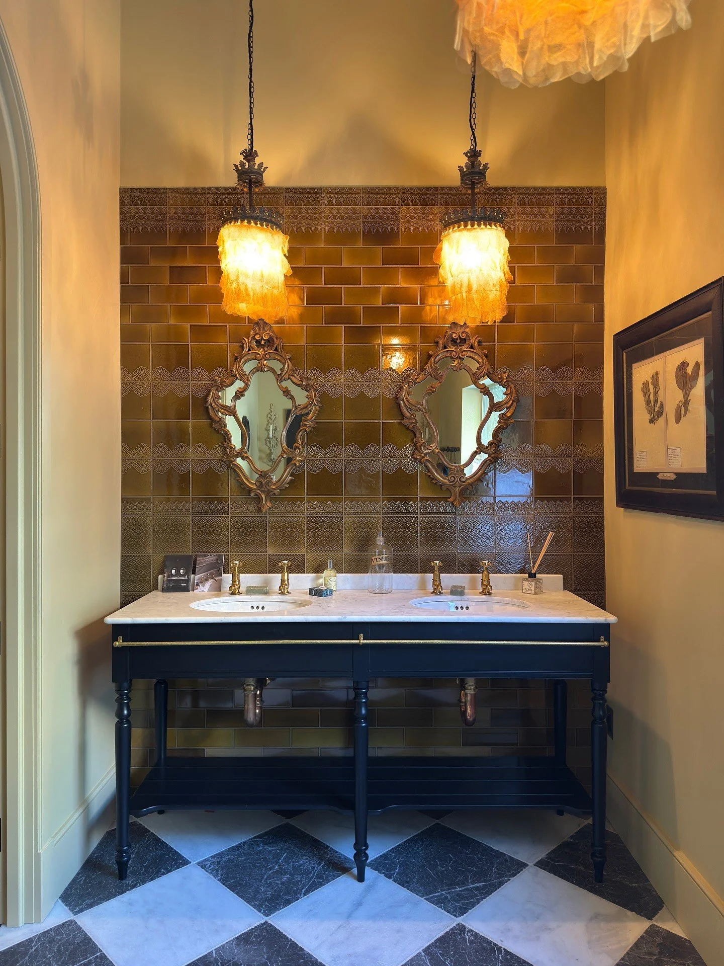 Dark vanity with brass fittings and a black-and-white stone floor