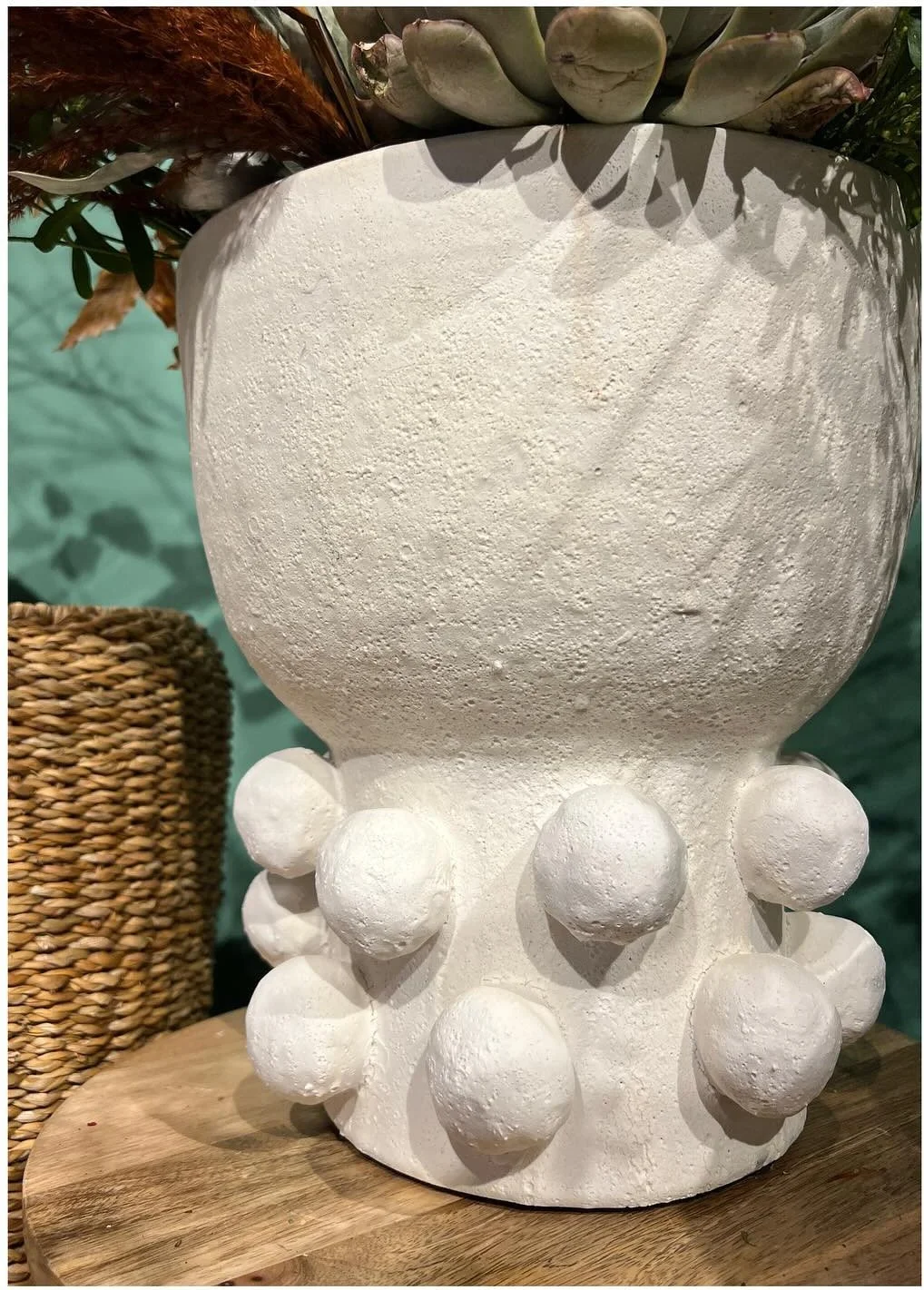 White textured ceramic planter set above rounded sculptural forms