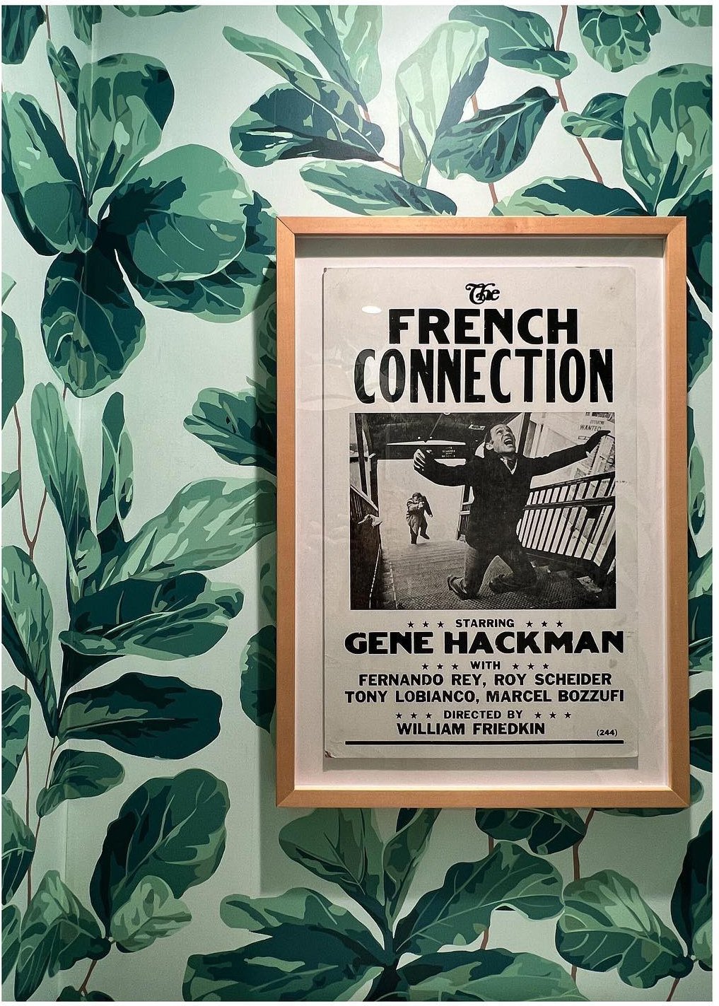 Framed French Connection poster against large green botanical wallpaper