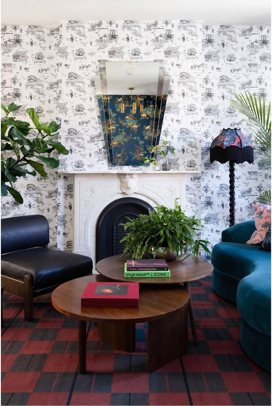 Teal sofa and vintage chairs against illustrated wallpaper