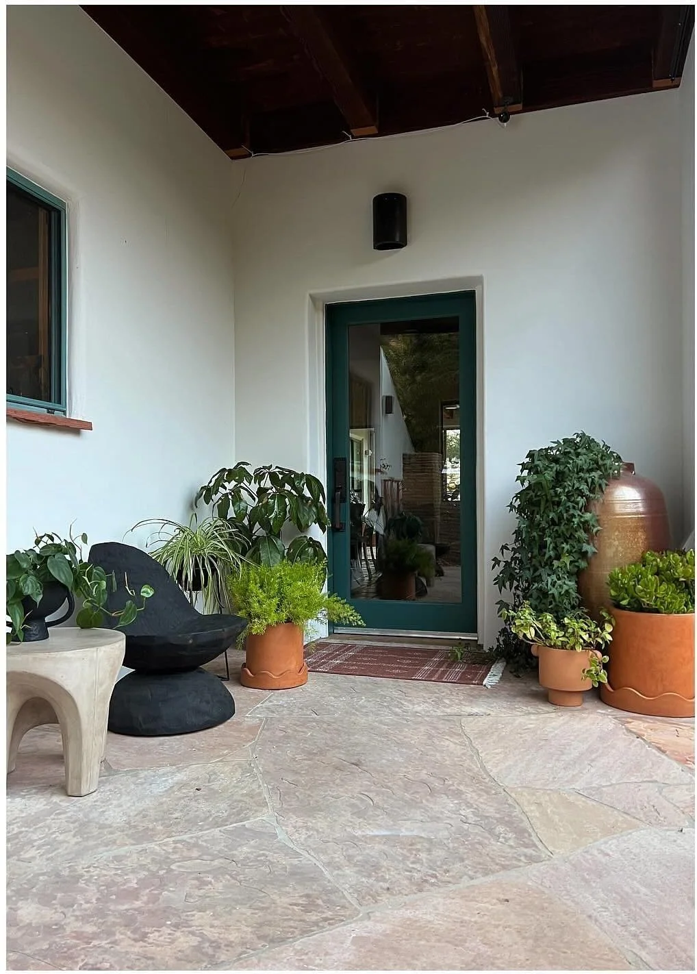 Potted plants beside an exterior doorway under a wood canopy