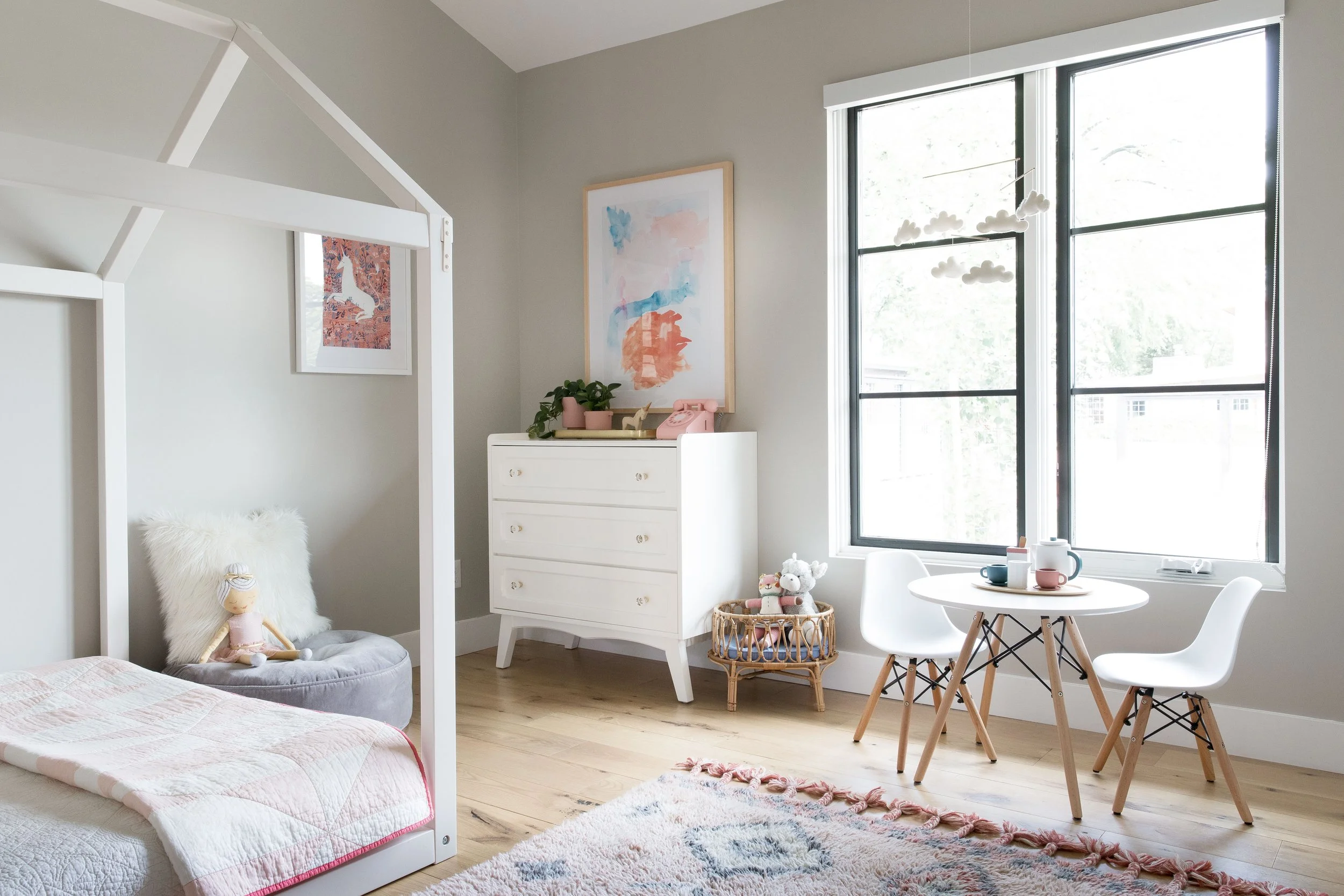 Child’s bedroom with a house-shaped bed, small table, and large window.